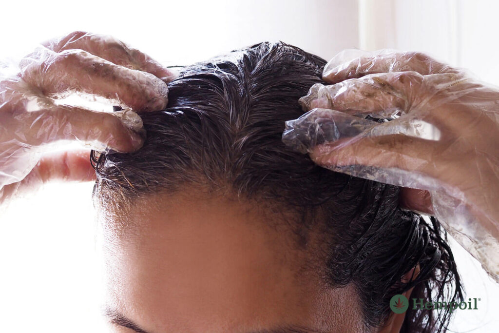 Woman applies a recipe with hemp oil and virgin olive oil to her hair.