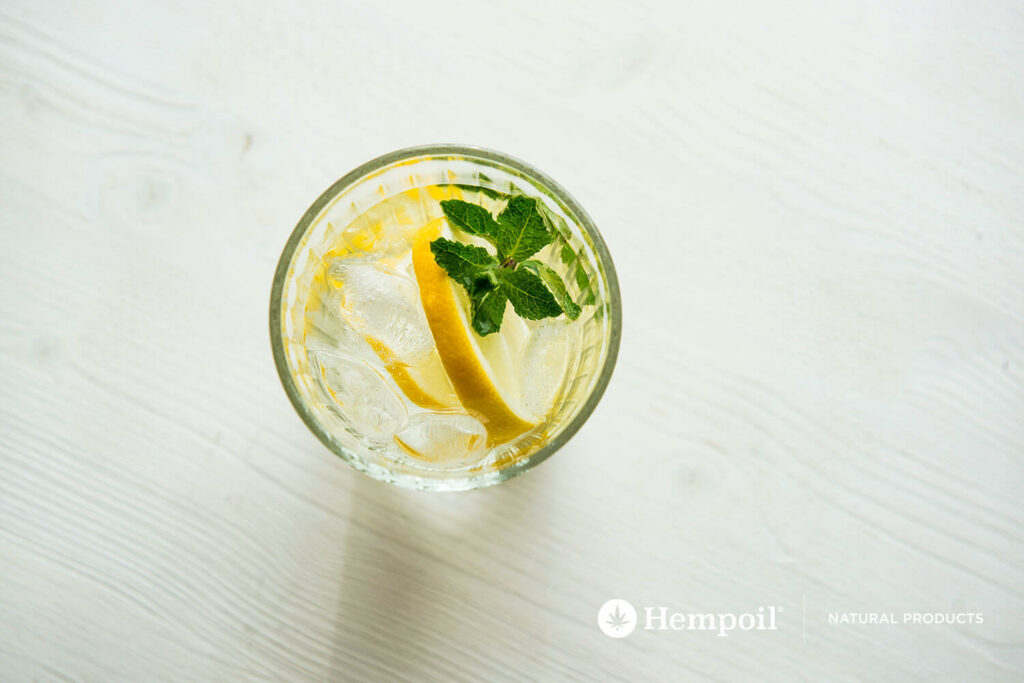 Glass of water with ice cubes, herbs and cannabis drops.